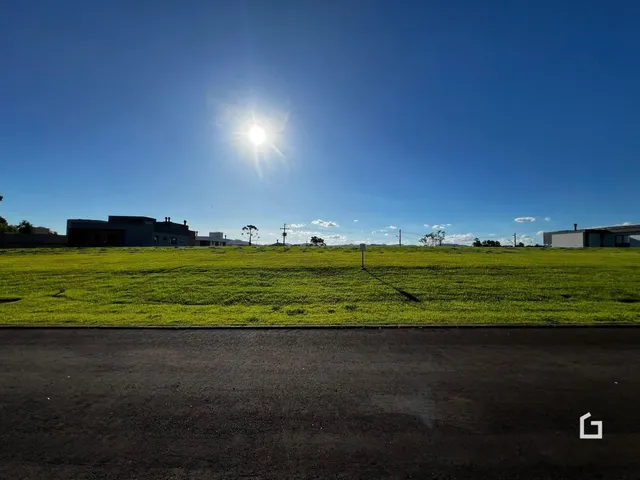 Vista externa de uma propriedade com campo gramado e horizonte sob um céu azul.