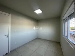 Vista interna de um corredor com paredes brancas e piso de cerâmica.