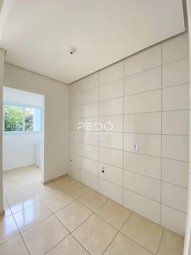 Interior de um corredor com paredes brancas e piso de cerâmica clara.