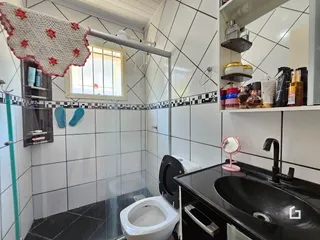 Interior de um banheiro com revestimento cerâmico e box de vidro.