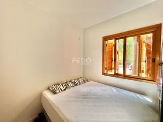 Quarto com cama e janela de madeira em um imóvel no Brasil.