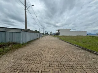 Vista externa da propriedade mostrando um muro de metal e um edifício branco no horizonte.