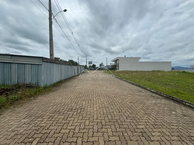 Vista externa da propriedade mostrando um muro de metal e um edifício branco no horizonte.