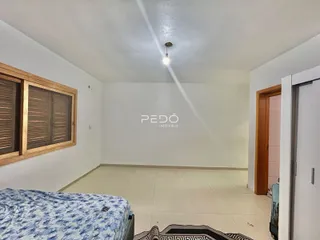 Quarto com janela de madeira e piso de cerâmica em imóvel no Brasil.