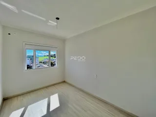 Ambiente interno de uma sala com piso de madeira e vista para o exterior.