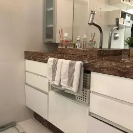 Foto de um banheiro com bancada de granito e armários brancos.