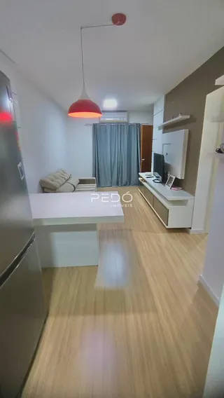 Ambiente interno de uma sala de estar com piso de madeira clara.