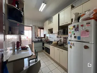 Imagem de uma cozinha com armários brancos e piso cerâmico.