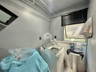 Interior de um cômodo com máquina de lavar roupa e janela.