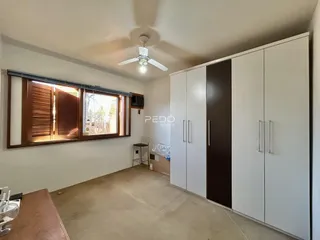 Ambiente interno de uma sala com janelas de madeira e armários embutidos.