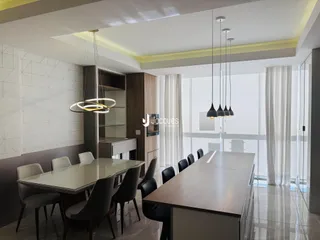 Vista de uma sala de jantar moderna com mesa de vidro e cadeiras escuras.
