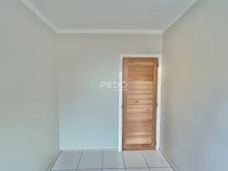 Vista de um corredor interno com paredes brancas e piso de cerâmica.