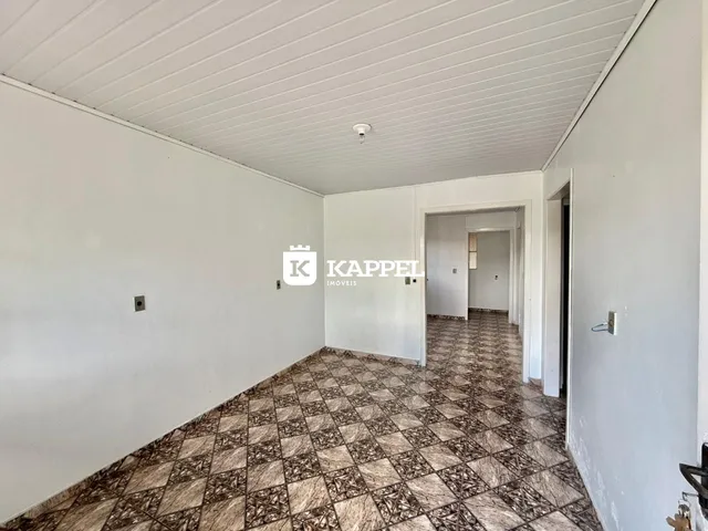 Um corredor interno com piso de ladrilhos marrons e teto de painel branco.