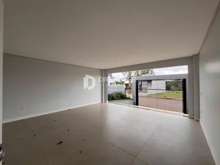 Espaço interno amplo com paredes brancas e piso de concreto.