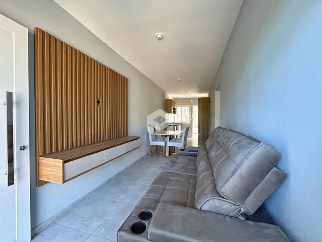 Sala de estar com sofá cinza e parede de madeira no interior da residência.