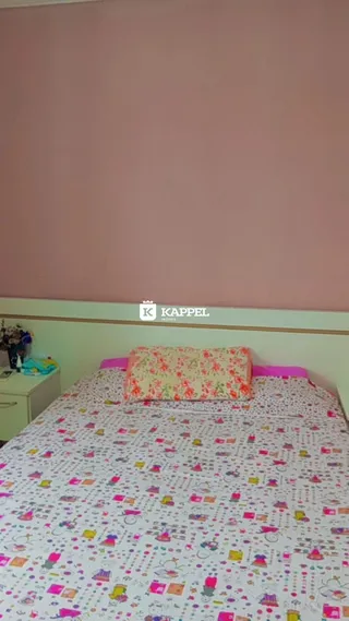 Quarto com cama coberta por lençóis coloridos.