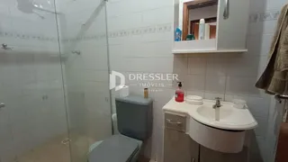 Banheiro com box de vidro e revestimento branco.