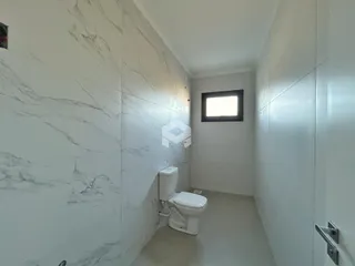Corredor interno com revestimento de mármore branco e vaso sanitário.