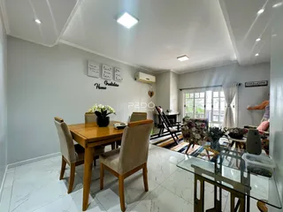 Sala de jantar com mesa de madeira e piso claro.