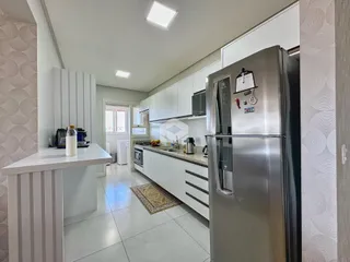Imagem de uma cozinha moderna com armários brancos e eletrodomésticos de aço inoxidável.