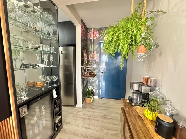Interior de uma sala com armário de vidro e geladeira em Lajeado.