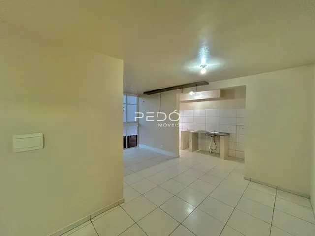Vista de um corredor interno com piso de cerâmica branca.