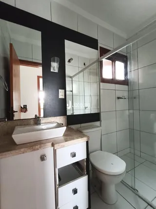 Foto de um banheiro com revestimento cerâmico e box de vidro.