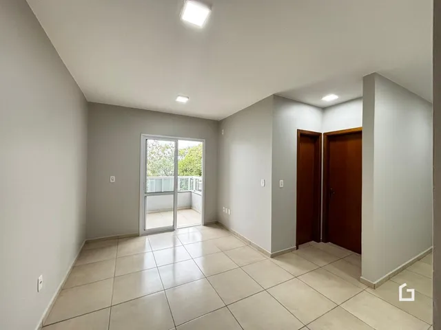 Interior de uma sala com piso de cerâmica e porta de vidro abrindo para uma varanda.