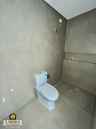 Foto de um banheiro com azulejos claros e vaso sanitário branco.