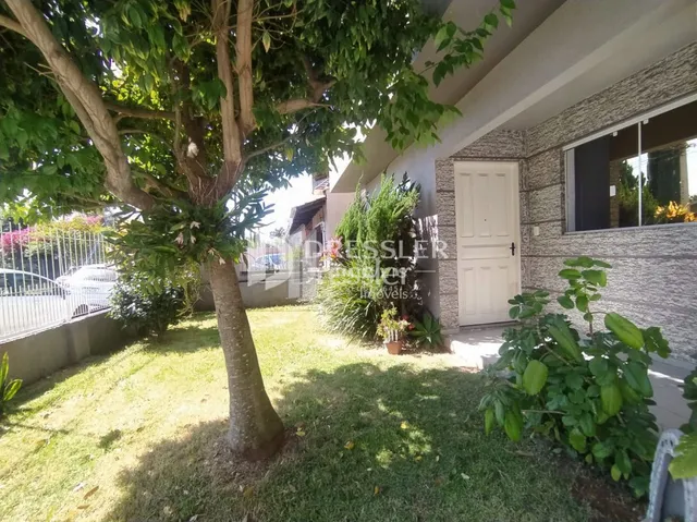 Fachada de uma residência com jardim e árvore na frente