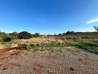 Vista externa de uma área pavimentada com tijolos vermelhos em um terreno aberto.