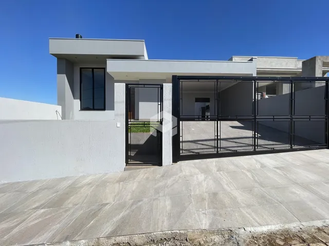 Fachada moderna de uma residência em Lajeado, Brasil, com muro branco e portão de metal.