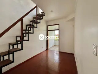 Hall de entrada com escadaria de madeira e piso polido.