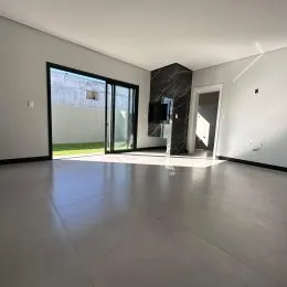 Sala de estar ampla com piso escuro e porta de vidro que dá acesso ao exterior.