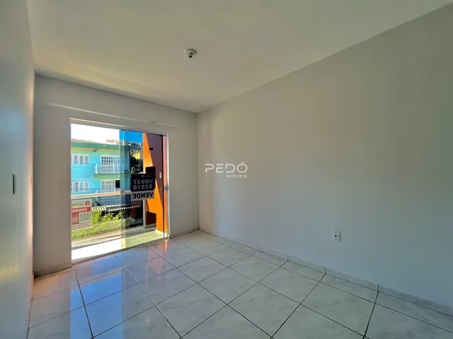 Interior de uma sala com piso de cerâmica e porta de vidro.