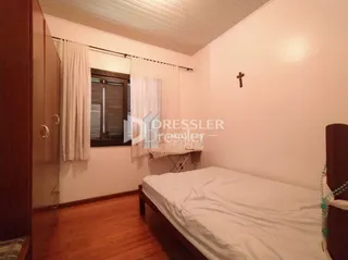 Quarto com piso de madeira e paredes claras em uma residência.