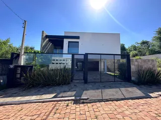 Fachada de uma residência em Lajeado, Brasil, com cerca e paisagismo na frente.