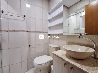 Banheiro com revestimento branco e bancada de mármore clara.