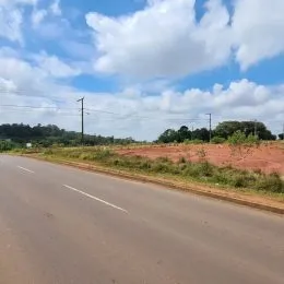 Vista de uma estrada rural sob um céu azul com nuvens.