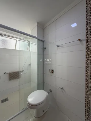 Banheiro moderno com box de vidro e piso cerâmico claro.