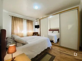 Quarto com cama e cortinas em madeira no interior da propriedade.