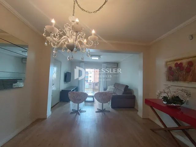 Hall de entrada com piso de madeira e luminária de cristal.