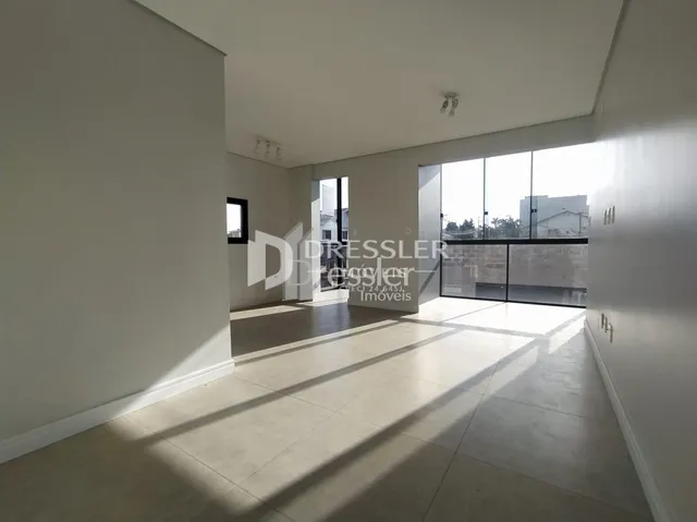 Interior de um ambiente com piso claro e paredes brancas iluminado pela luz natural.