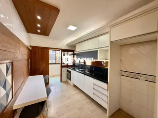 Foto de uma cozinha com armários brancos e bancada escura em um imóvel brasileiro.