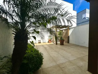 Área externa com piso de concreto e vegetação.