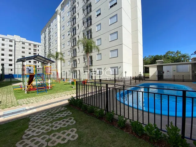 Vista externa de um prédio residencial com piscina e área verde em Lajeado.