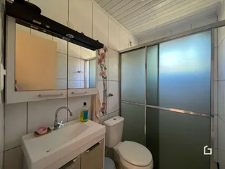 Foto de um banheiro com azulejos brancos e louças sanitárias.