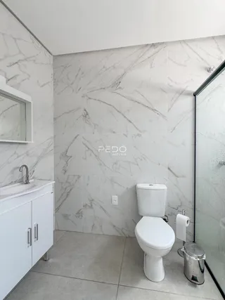 Banheiro com revestimento de mármore branco nas paredes.