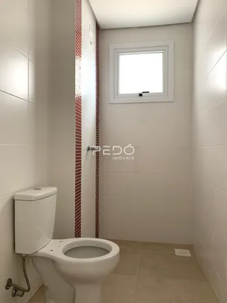 Foto interna de um banheiro com azulejos brancos e vermelhos.
