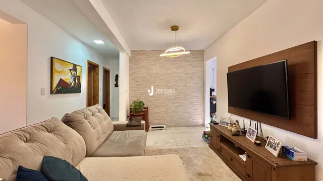 Sala de estar com sofá e painel de TV em ambiente claro.